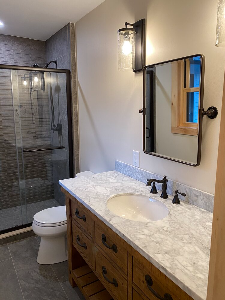 A bathroom with a toilet , sink , mirror and shower.