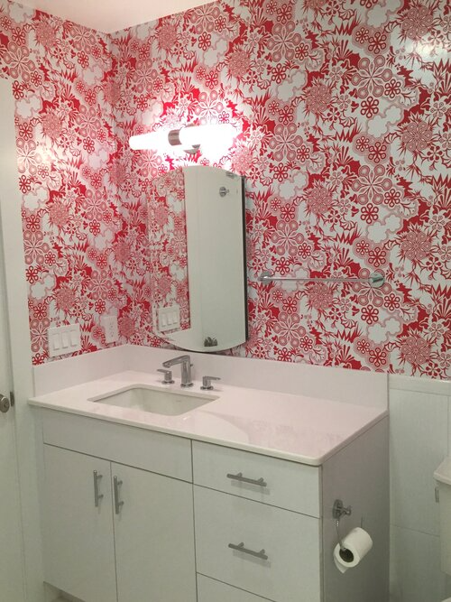 A bathroom with red and white wallpaper and a sink