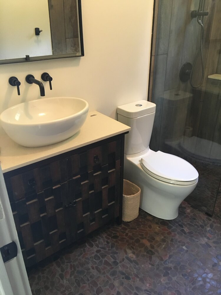 A bathroom with a toilet , sink and mirror