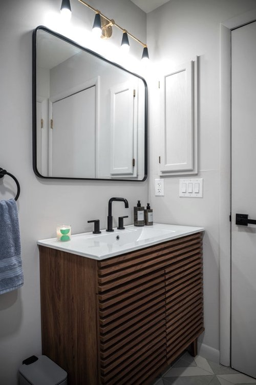 A bathroom with a sink , mirror and towel rack.