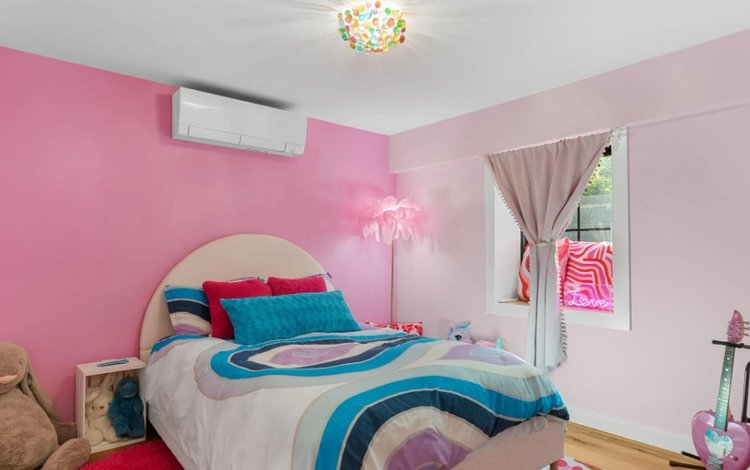 A bedroom with pink walls , a bed , a lamp and a window.