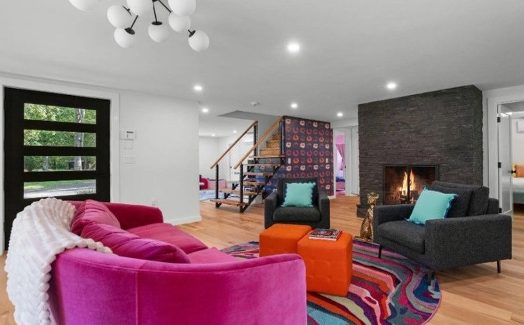 A living room with a pink couch and a fireplace