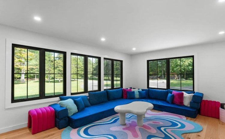 A living room with a blue sectional couch and a pink rug.