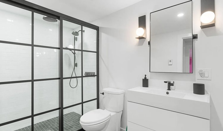 A bathroom with a toilet , sink , shower and mirror.