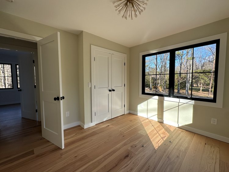 An empty room with hardwood floors and two windows.