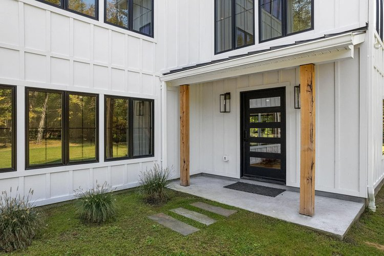 The front of a white house with black windows and a black door.