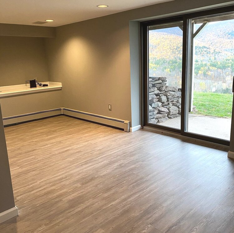 An empty room with hardwood floors and a large window.