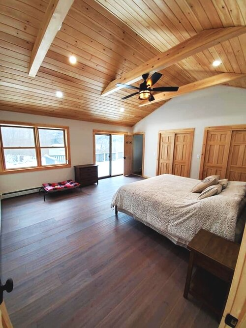 A bedroom with a large bed and a ceiling fan.