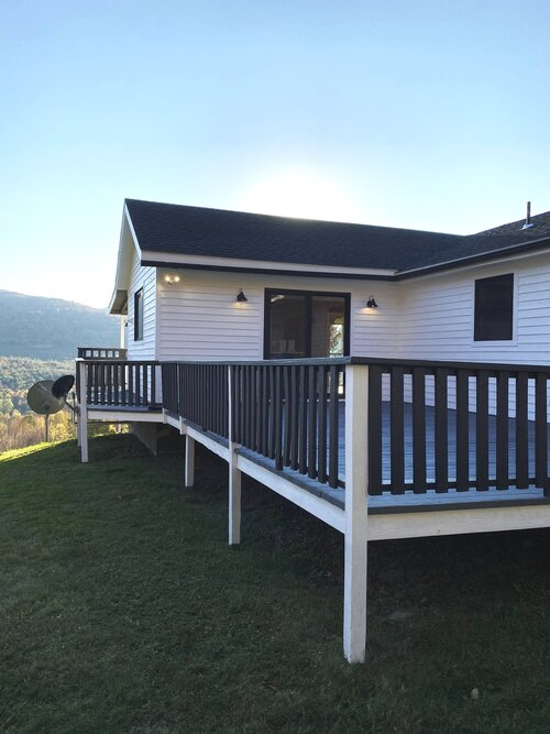 A white house with a large deck and a black railing