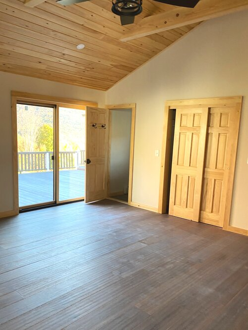 An empty room with sliding glass doors and a ceiling fan.