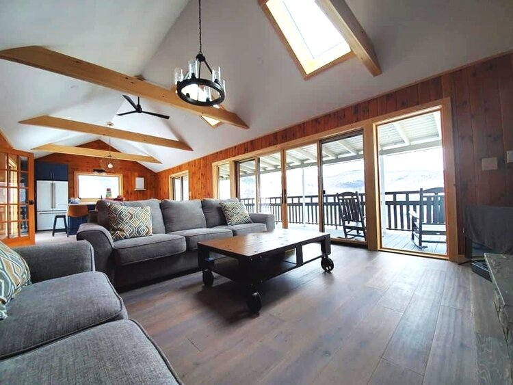 A living room with a couch , chair , coffee table and lots of windows.