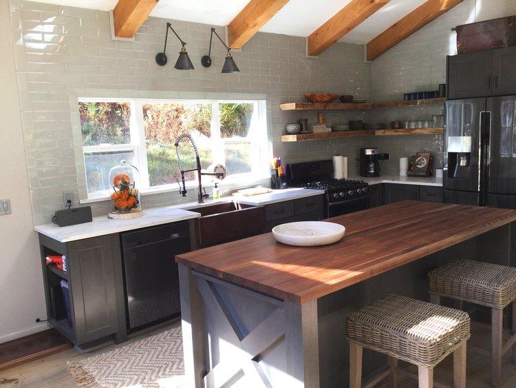 A kitchen with a large wooden table and stools