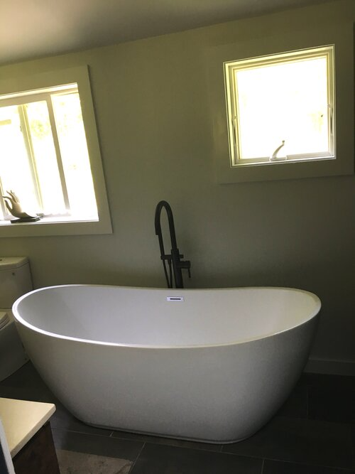 A white bathtub is sitting in a bathroom next to a window.