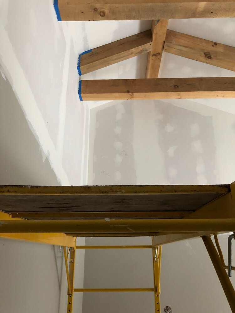 A yellow scaffolding is sitting under a ceiling with wooden beams.