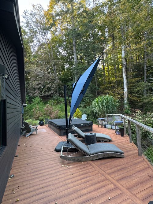 A wooden deck with a blue umbrella and lounge chairs.