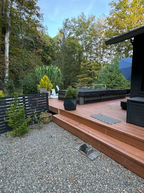 A wooden deck with stairs leading up to it and trees in the background.