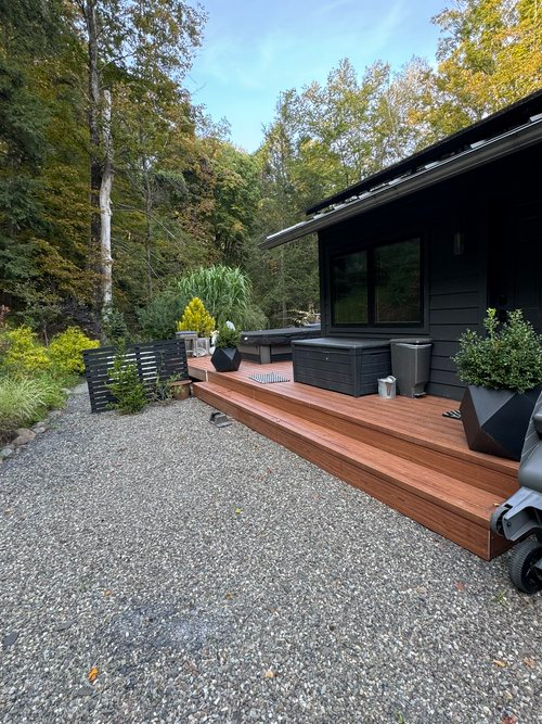 A black house with a wooden deck and stairs in front of it.