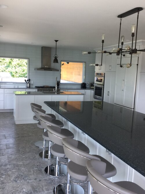 A kitchen with a long black counter top and stools