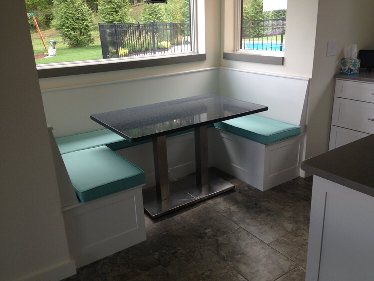 A kitchen with a table and benches in front of a window
