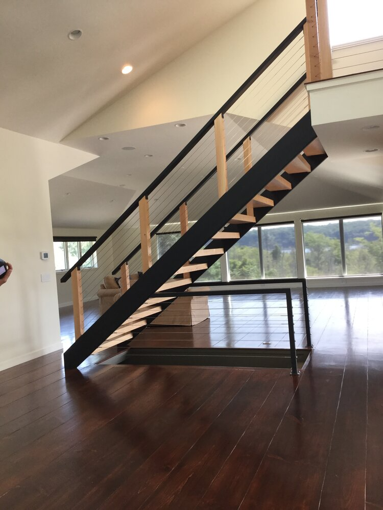 A wooden staircase with a black railing in an empty room