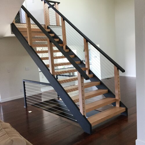 A wooden staircase with a black railing in a living room