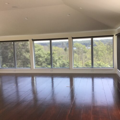 An empty room with hardwood floors and lots of windows