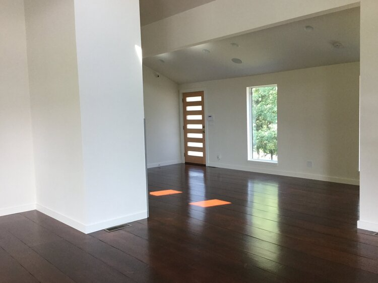 An empty living room with hardwood floors and white walls