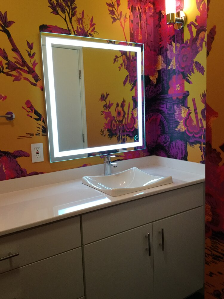 A bathroom with a sink and a mirror with flowers on the wall
