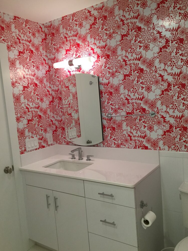 A bathroom with red and white wallpaper and a sink
