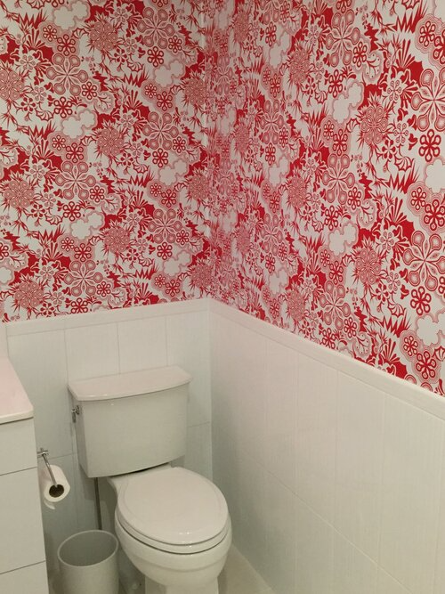 A toilet in a bathroom with red and white wallpaper