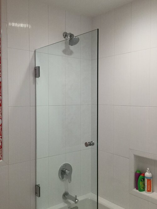 A bathroom with a glass shower door and a bathtub.