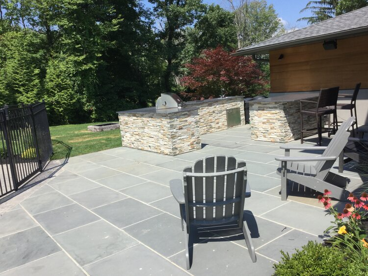 A patio with chairs and a grill in the backyard