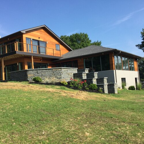 A large house sits on top of a grassy hill