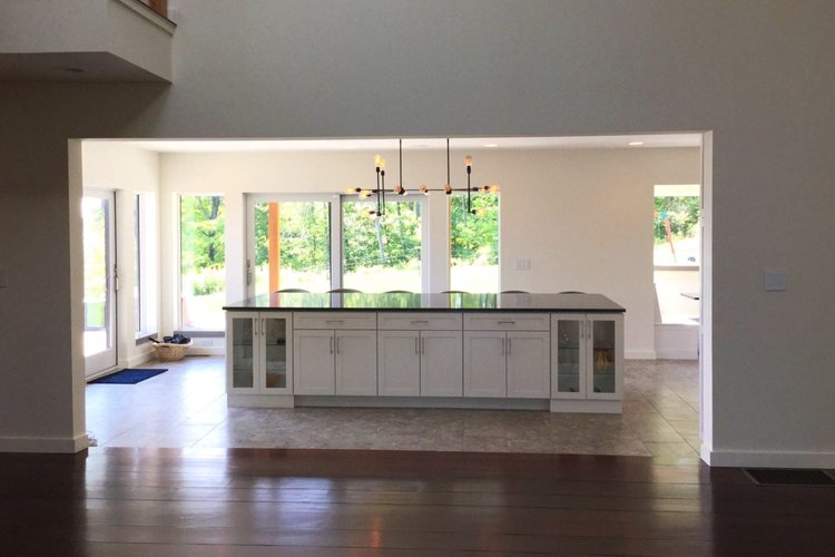 An empty kitchen with white cabinets and a large island