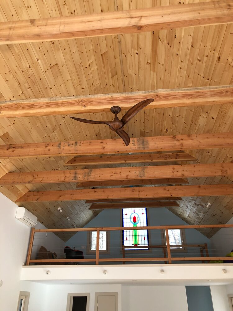 A ceiling fan is hanging from the ceiling of a room with wooden beams.