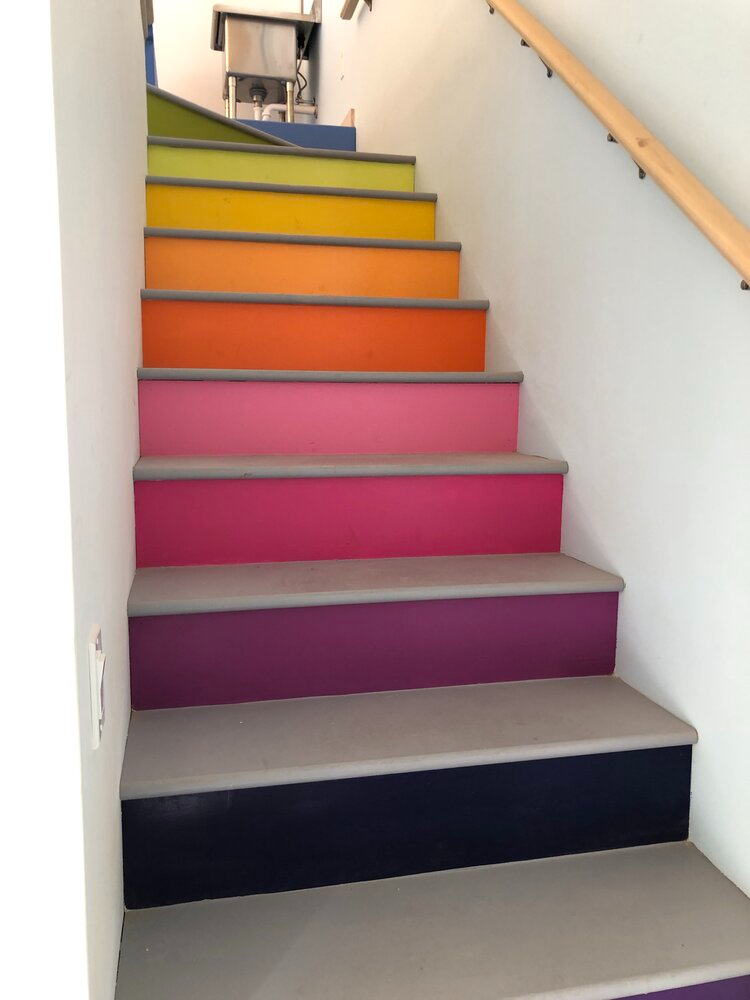 A set of colorful stairs with a wooden railing