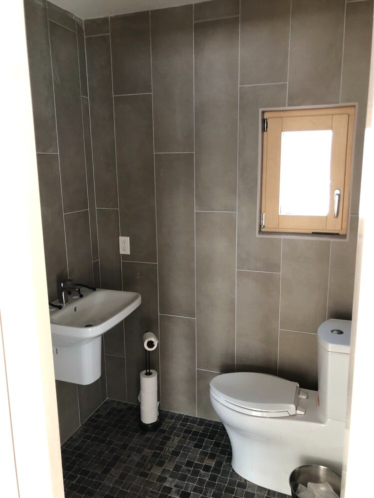 A bathroom with a toilet , sink , and window.