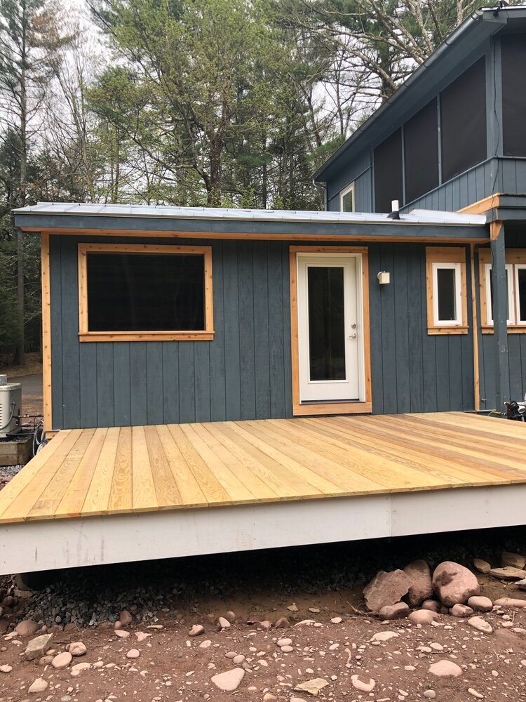 A blue house with a wooden deck in front of it.