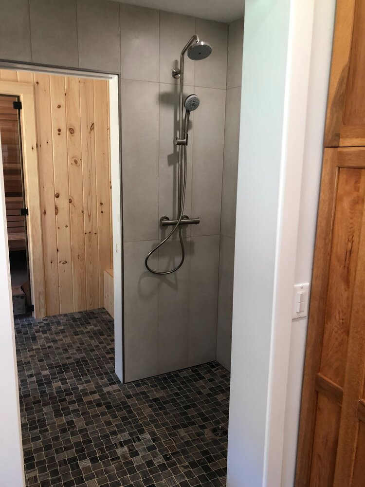 A bathroom with a walk in shower and a wooden door.