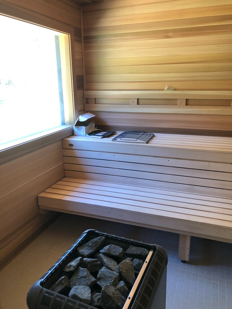A wooden sauna with a bench and a window.