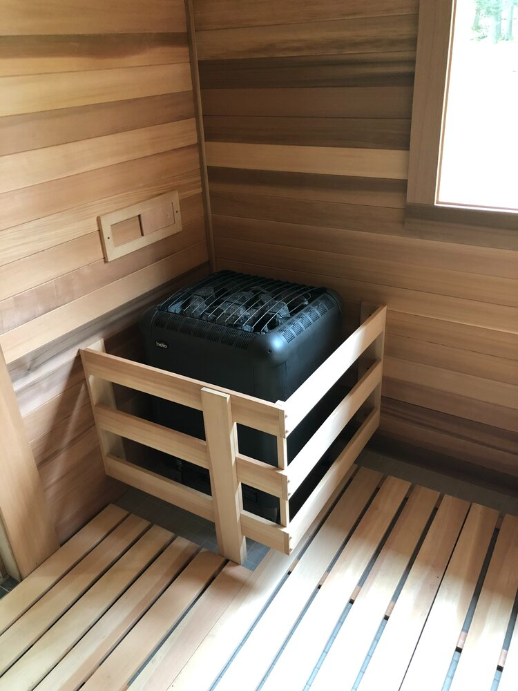 A wooden sauna with a heater in the corner