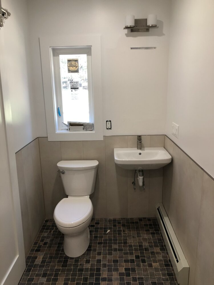 A bathroom with a toilet , sink and window.