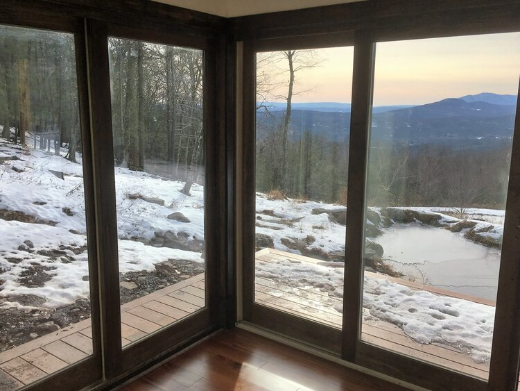 A room with a view of a snowy landscape through the windows.
