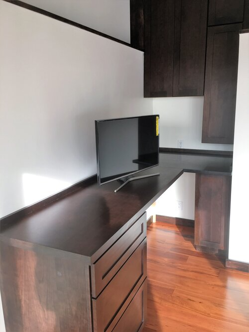 A flat screen tv sits on a desk in a kitchen