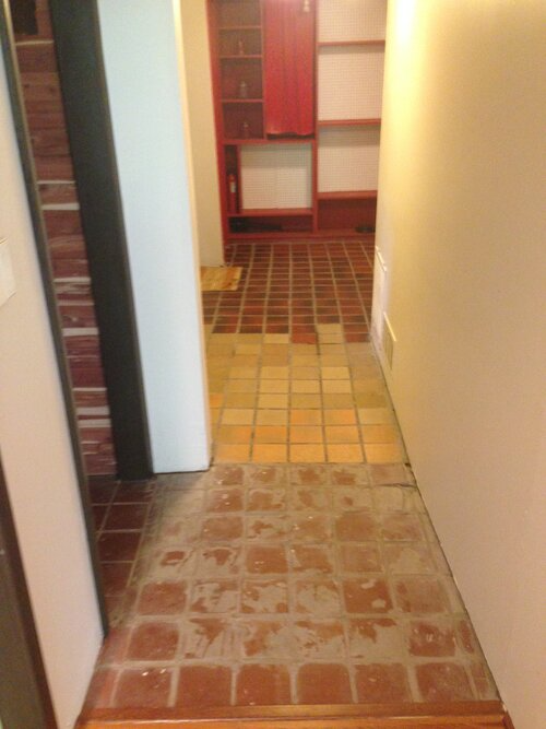 A hallway with a brick floor and a white wall