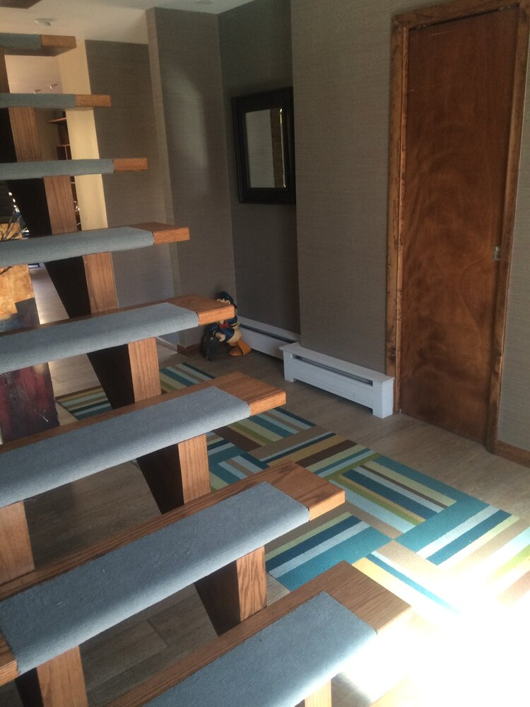 A hallway with stairs and a mirror on the wall