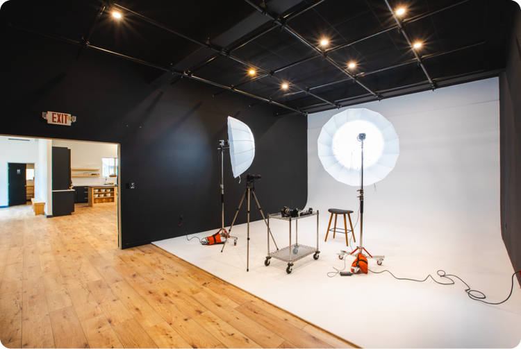 A photo studio with a wooden floor and a white wall.