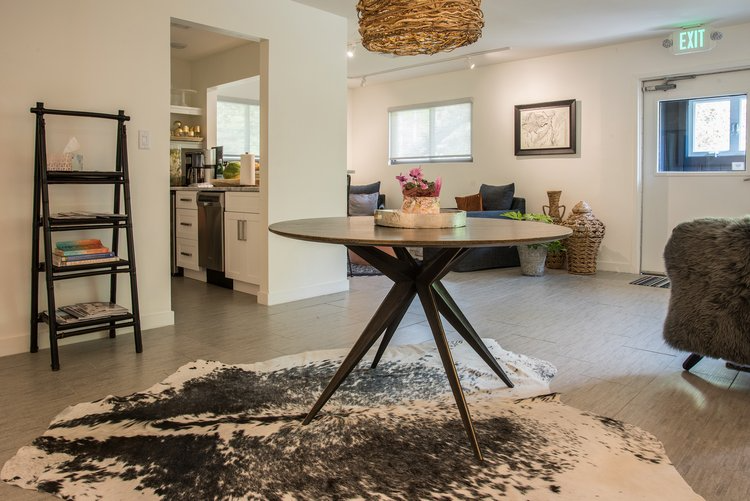 A living room with a round table and a rug on the floor.