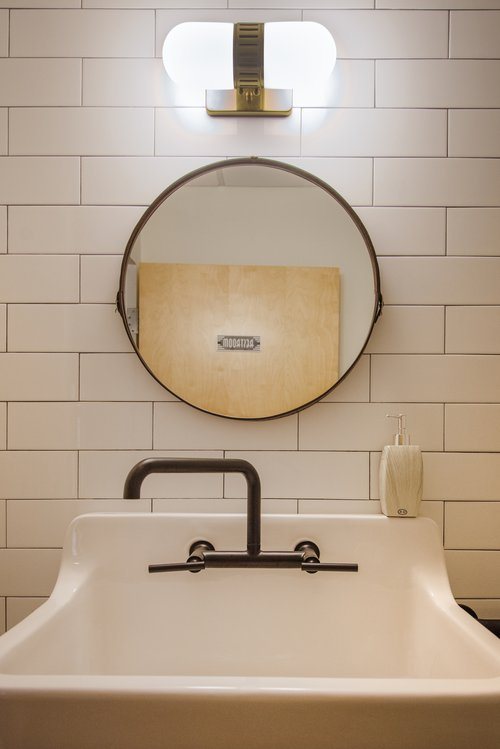 A bathroom sink with a round mirror above it.