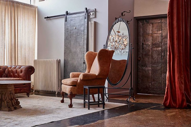A living room with a couch , chair , table and mirror.